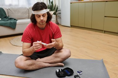 Genç bir adam evde kendi kendine bakım yapıyor, rahatça otururken kan şekerini ölçüyor..