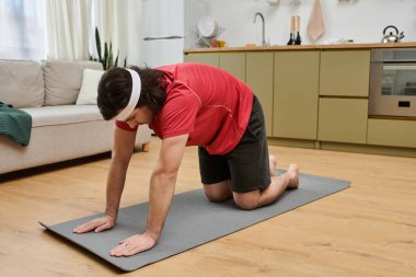 Spor meraklısı, apartmanındaki spor minderinin üstünde spor yapıyor..