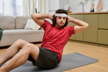 Genç adam evde dinlenirken bir spor minderinde karın egzersizi yapıyor..