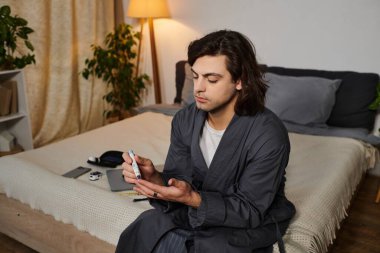 Genç adam diyabet rutinini evde uyguluyor, kan şekerini ölçüyor ve sağlığını dengeliyor..