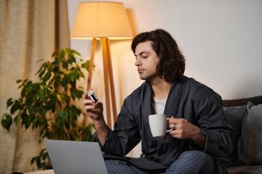 Kafkasyalı genç adam modern dairesinde kahve içerken kan şekerini ölçüyor..