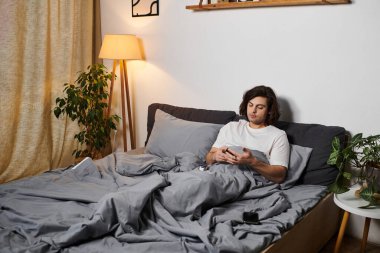 Genç adam sağlığını kontrol ediyor ve evde yatağında dinlenirken diyabetini kontrol ediyor..