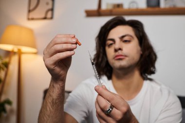 A young man demonstrates his daily health management while preparing his insulin at home. clipart