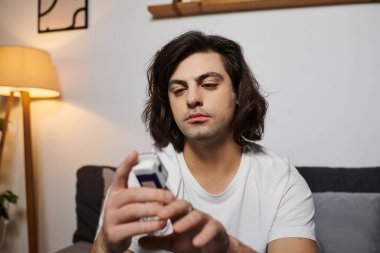 Uzun saçlı beyaz bir adam sabahları modern bir dairede kan şekerini ölçüyor..