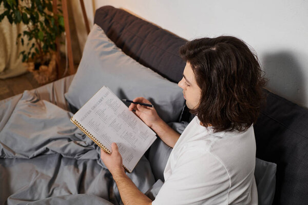 Молодой человек тщательно отслеживает уровень сахара в крови дома, расслабляясь в постели.