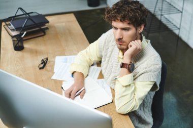 Young professional with curly hair engaged in projects at a stylish corporate workspace. clipart