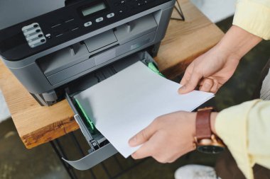 Süveter giyen kıvırcık saçlı bir adam şık bir ofis masasında etkili bir şekilde çalışıyor..
