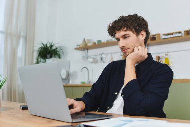 Kıvırcık saçlı yakışıklı genç adam şık ofis düzeninde çalışıyor..