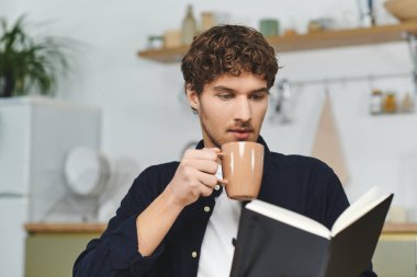 Kıvırcık saçlı adam, rahat, modern evlerinde kahve ve güzel bir kitapla rahatlıyor..