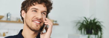 Kıvırcık saçlı yakışıklı genç bir adam modern bir ortamda evde telefon konuşmasından hoşlanıyor.