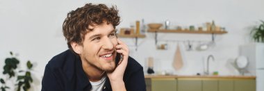 Parlak ve neşeli kıvırcık saçlı adam evde dinlenirken telefonda konuşuyor.