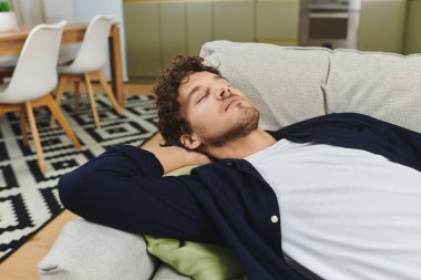 Kıvırcık saçlı yakışıklı genç adam evde dinlenmenin tadını çıkarıyor..