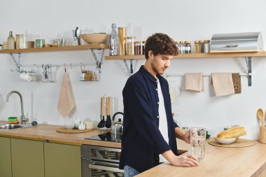 Kıvırcık saçlı yakışıklı genç adam şık mutfağında kaynaşmaya odaklanıyor..