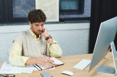 Modern bir ofiste çalışan genç bir profesyonel çalışırken özenle not alıyor..