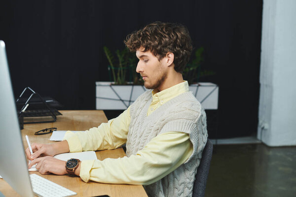 Молодой человек в жилете в свитере занимается своей работой в гладкой корпоративной среде.