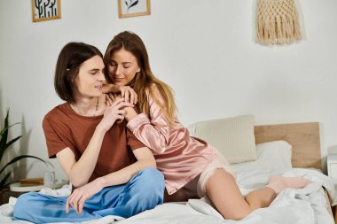 Şık genç bir çift, yumuşak dekorlarla çevrili rahat bir yatakta kahkaha ve şefkat paylaşır..