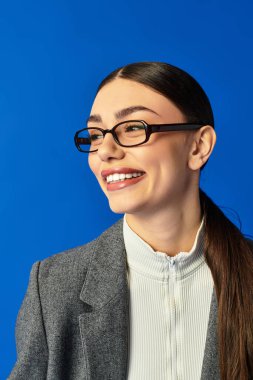 Uzun saçlı ve gözlüklü genç bir kadın mutlulukla parıldıyor, kendine güvenini ve duygularını gösteriyor..