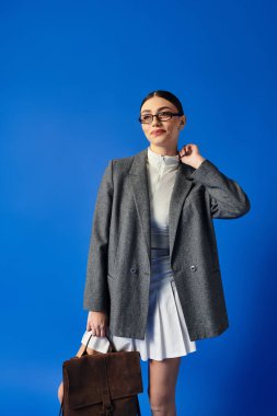 Genç bir kadın şık elbisesi ve şık çantasıyla kendinden emin bir şekilde hava atıyor..