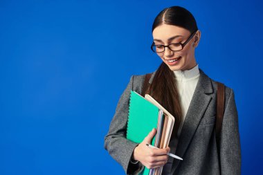 Bright expression on a young womans face as she embraces her notebooks with joy. clipart