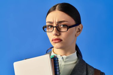 Güzel, genç bir kadın elinde defterlerle dikiliyor, merakını ve dikkatini gösteriyor..