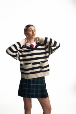 Genç bir kadın çizgili bir süveter içinde oyuncu ve duygusal yanını sergiliyor..