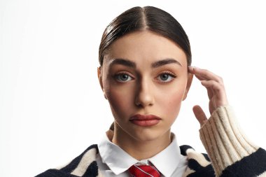 Genç bir kadın, düşüncelerinde kaybolan şakağına nazikçe dokunurken bir dizi duygu sergiliyor..