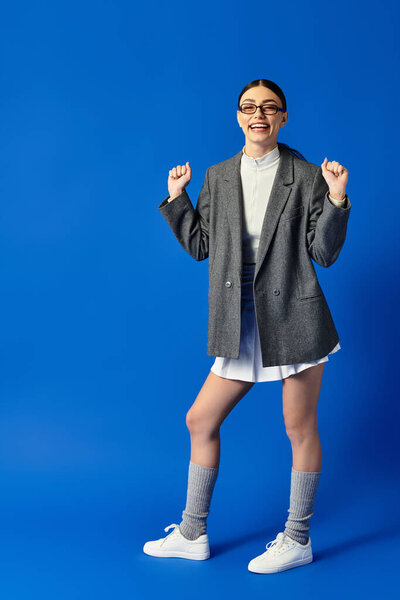 Молодая красивая эмоциональная женщина сияет от радости, празднуя свой стиль и энергию.