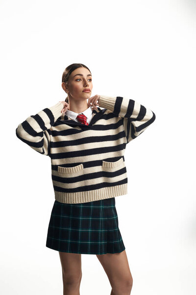 Молодая женщина уверенно показывает свою игривую и эмоциональную сторону в полосатом свитере.