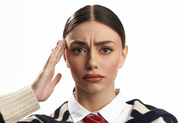A young woman expresses contemplation and concern, hand on her head.