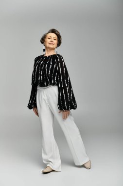 A stunning woman in her 60s poses gracefully in fashionable attire, exuding confidence and elegance. clipart