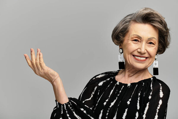 A beautiful woman in her 60s radiates style and confidence while posing elegantly.