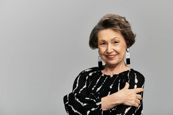 A stylish woman in her 60s poses gracefully in trendy attire.