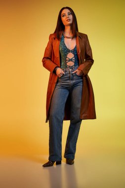 Güzel, genç bir kadın yılan desenli elbisesiyle ayakta duruyor, göz kamaştırıcı makyajını sergiliyor..