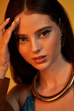 Çekici genç bir kadın göz alıcı sanatsal makyajla şık bir kıyafet içinde poz veriyor..