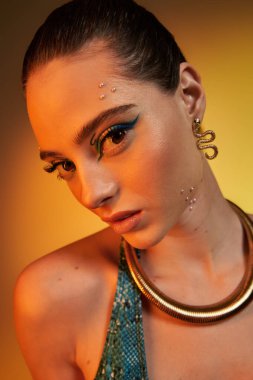 Yılan desenli çarpıcı bir model sıcak bir arka planda rahatça poz veriyor..