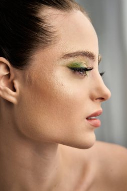 Genç bir kadın stüdyoda yeşil makyaj modelliği yapıyor..