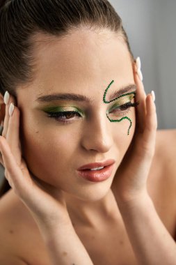 A beautiful young woman displays intricate snake-inspired makeup, embodying modern beauty trends. clipart