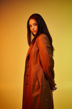 Paltolu güzel genç bir kadın kendine güvenerek poz veriyor, zarafet ve cazibe yayıyor..