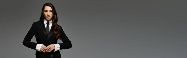 A beautiful young woman with long brown hair showcases a fashionable outfit in a studio setting, banner