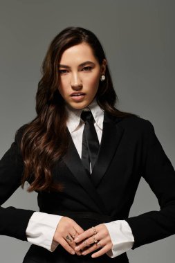 Uzun kahverengi saçlı güzel bir genç kadın şık siyah beyaz elbiseler giyiyor..