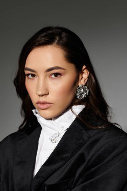 Parlak kahverengi saçlı genç bir kadın zarif ve kendine güvenen entellektüel kıyafetine sahip..