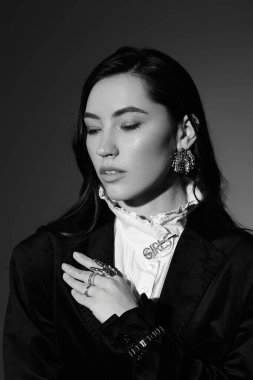 Parlak kahverengi saçlı genç bir kadın şık bir elbise içinde zarifçe poz verir..