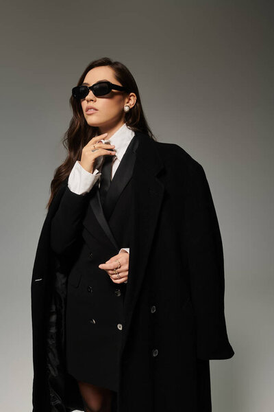 Красивая молодая женщина демонстрирует свое чувство моды с длинными каштановыми волосами и стильный наряд.