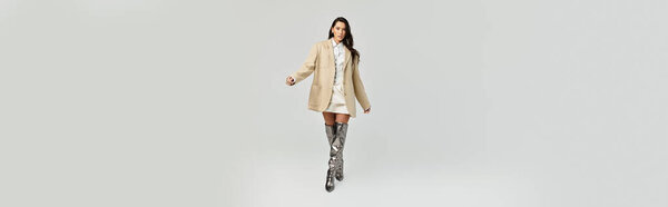 A beautiful young woman showcases her trendy ensemble while walking with confidence.