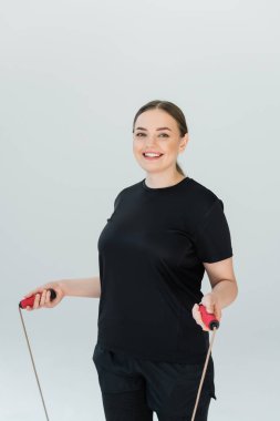 Enerjik kadın ip atlıyor, gücünü ve uygunluğunu parlak bir ortamda gösteriyor..
