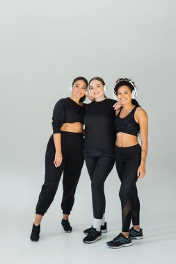 Three fit women in stylish sportswear embody strength and camaraderie in a bright space. clipart