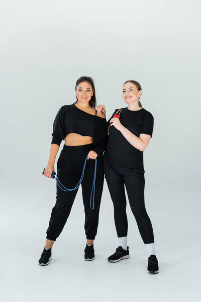 Two fit women stand confidently in stylish sports attire, showcasing strength and camaraderie.