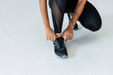 Formda bir kadın spor yapmak için spor ayakkabılarını bağlar, gücünü ve stilini gösterir..