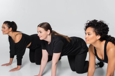 Çağdaş bir fitness alanında odaklanma ve güç gösteren üç güçlü kadın birlikte egzersiz yapıyor..