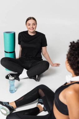 İki zinde kadın yoga minderlerinde dinleniyor, canlandırıcı bir çalışmadan sonra sohbet ediyorlar..